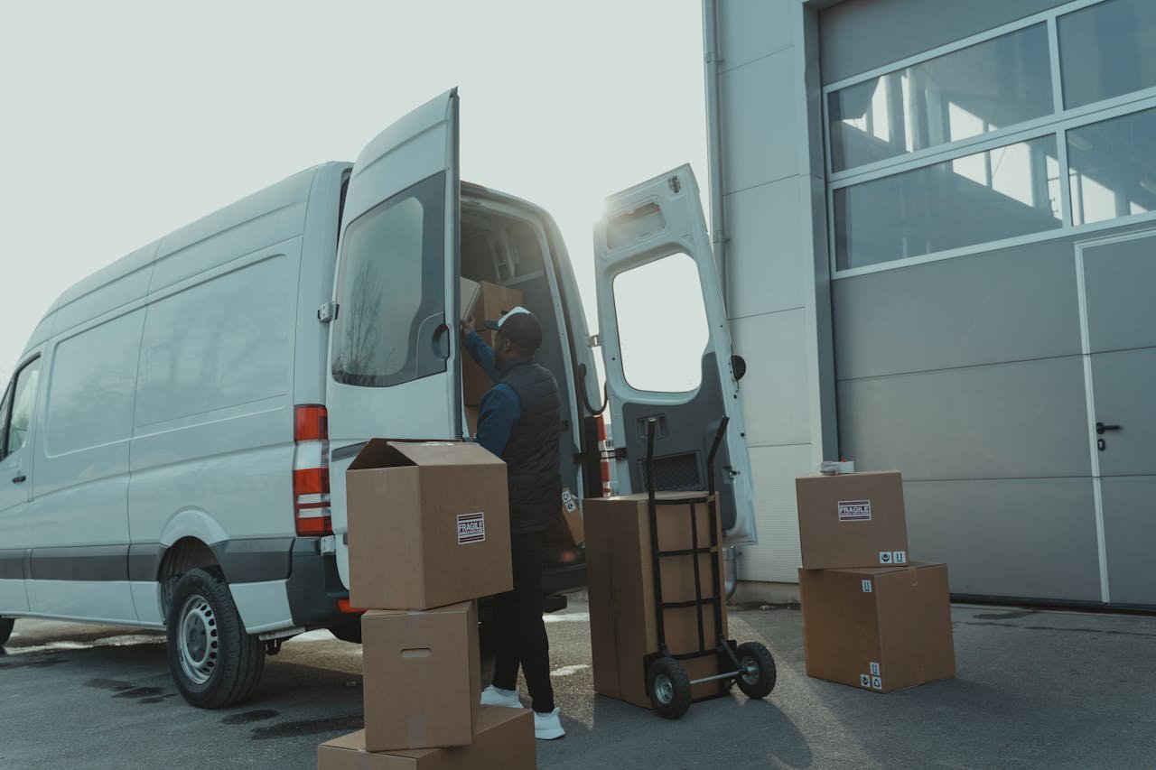 portfolio-06 Courier loading cardboard boxes into a delivery van outside a warehouse.